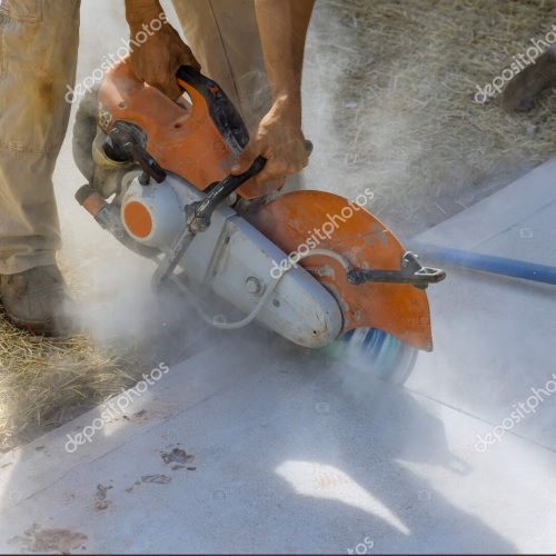 Construction worker uses diamond blade saw to cut concrete sidewalk